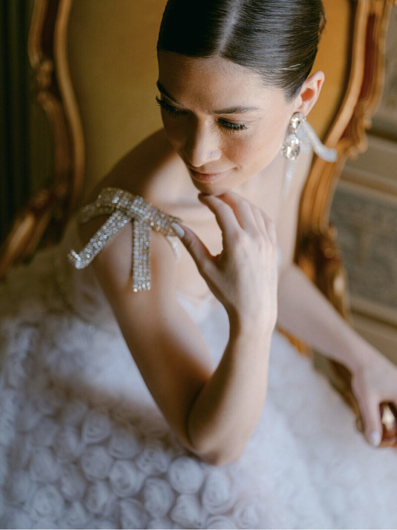 Bride wearing a crystal bow shoulder detail in warm portrait light